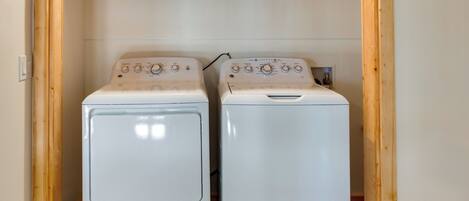 Two white front-loading washing machines in a wooden cabinet under a wooden beam.