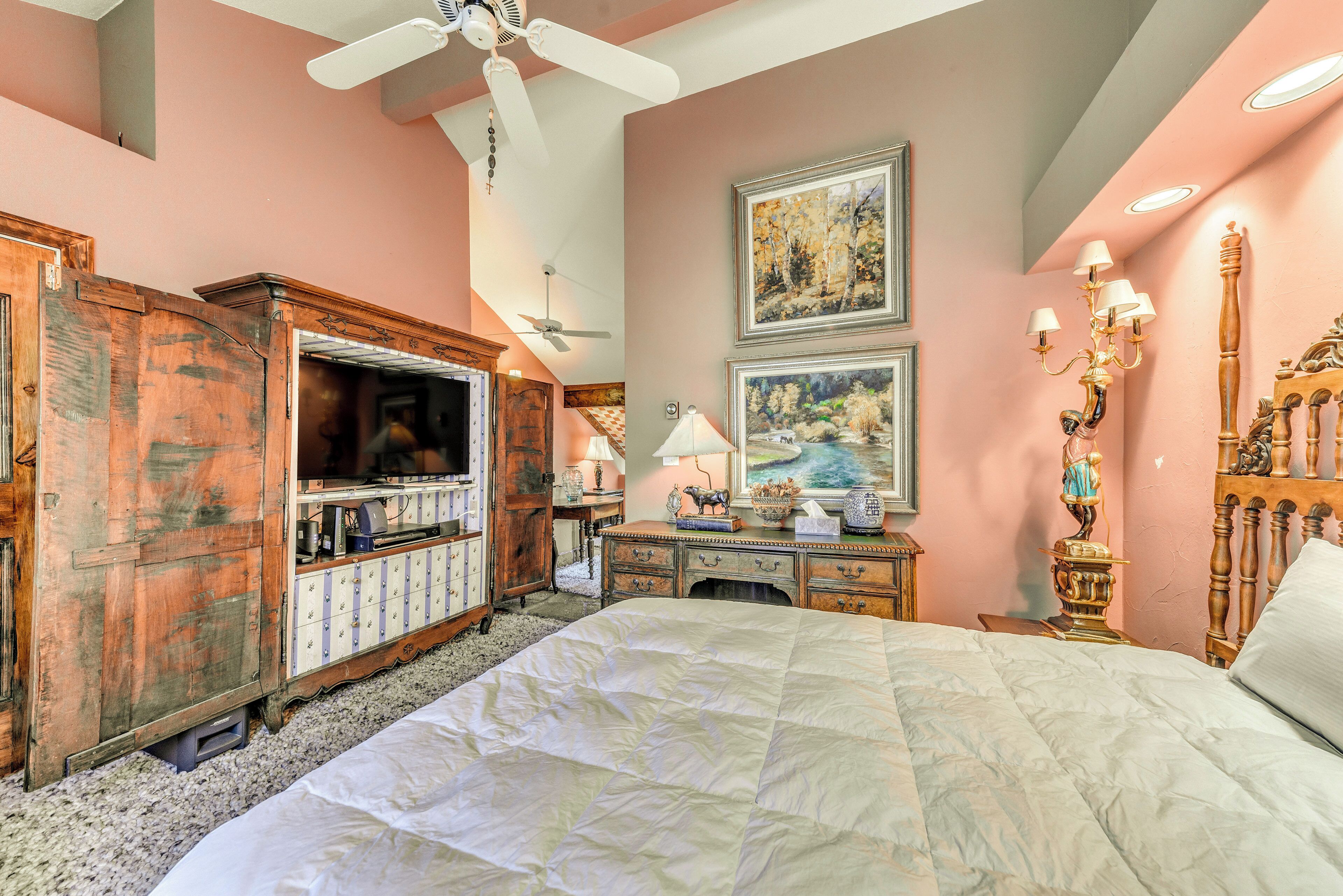 A bedroom with a bed, dresser, desk, and ceiling fan.