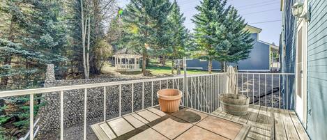 A wooden deck with a stone patio, a wooden bench, and a potted plant.
