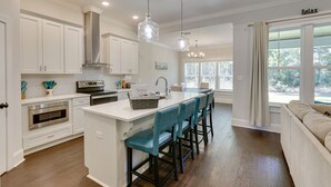 A modern kitchen with white cabinetry, a central island with bar stools, stainless steel appliances, and pendant lighting. - Family-friendly Crawfordville Home ~ 15 Mi to Fsu! (Crawfordville)