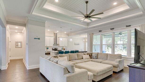 A spacious living room with a large sectional sofa, a ceiling fan, and a view of the kitchen in the background. - Family-friendly Crawfordville Home ~ 15 Mi to Fsu! (Crawfordville)