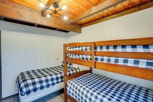 Una habitación con dos literas, vigas de madera en el techo y una lámpara.
