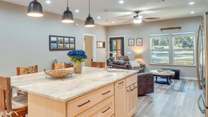A spacious kitchen with a large island, wooden cabinets, and pendant lighting.