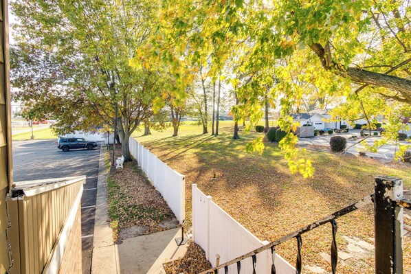 A residential area with a white fence, a pathway, and a parked car.