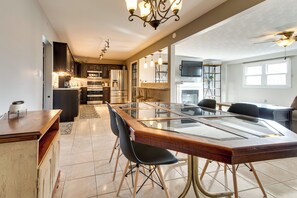 A spacious kitchen with modern appliances, a dining area with a glass-top table, and a ceiling fan.