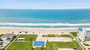 Un hotel sulla costa con vista sulla spiaggia, parcheggio e piscina.