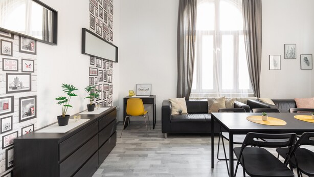 A modern living room with a sofa, dining table, and chairs, a small desk with a chair, and a large window with curtains. - FAMILY APARTMENT A/C FREE-BREAKFAST @OLD-TOWN (Budapest)