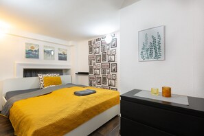 Une chambre à coucher avec un lit, une table de chevet, un mur orné de tableaux encadrés et une cheminée.