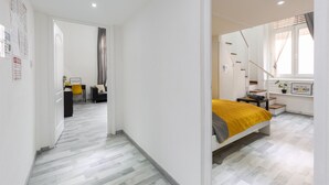 A modern bedroom with a bed, a desk, and a chair. There is a window with curtains and a mirror on the wall. - FAMILY APARTMENT A/C FREE-BREAKFAST @OLD-TOWN (Budapest)