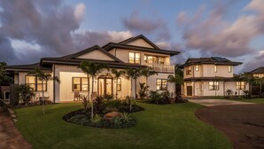 A two-story house with a well-maintained lawn, a driveway, and a balcony. - Hale Ho'okipa: 2 Homes/2 Pools in Poipu-Sleeps 16 (Koloa)