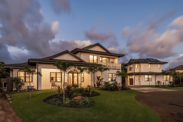 A two-story house with a well-maintained lawn, a driveway, and a balcony.