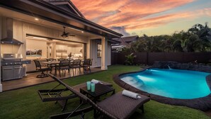 A modern house with a backyard featuring a swimming pool, outdoor dining area, and a kitchen with a large island. - Hale Ho'okipa: 2 Homes/2 Pools in Poipu-Sleeps 16 (Koloa)