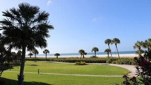 A well-maintained lawn with a pathway leading to a beach. - Gulf and Bay Club- F105 Beautiful unit and great location! (Siesta Key)