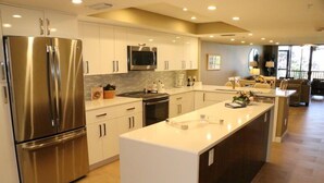 A modern kitchen with stainless steel appliances, white cabinetry, and a central island. - Gulf and Bay Club- F105 Beautiful unit and great location! (Siesta Key)