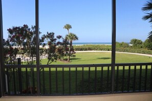 A view from a balcony with a clear view of a beach and ocean. - Gulf and Bay Club- F105 Beautiful unit and great location! (Siesta Key)