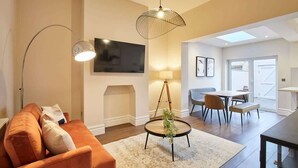Un salon moderne comprenant un canapé, une table basse avec une plante, un téléviseur et un coin repas avec une table et des chaises.