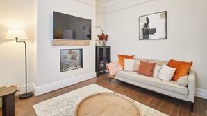 Un salon avec un canapé, une table basse, un lampadaire et des œuvres d’art accrochées aux murs.