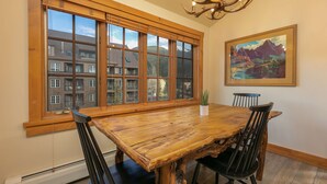 A dining area with a large wooden table, black chairs, a potted plant, and a painting on the wall. - Expedition Station Powder Days Condo: Ski In, Ski Out Keystone Retreat (Keystone)