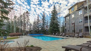 A pool area with lounge chairs, a small pool, and a building with balconies. - Expedition Station Powder Days Condo: Ski In, Ski Out Keystone Retreat (Keystone)