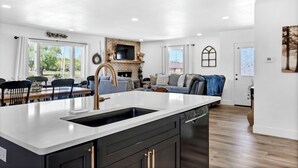 A modern kitchen with a large island, dark cabinetry, and a built-in oven. - Large Home In Haysville! (Haysville)