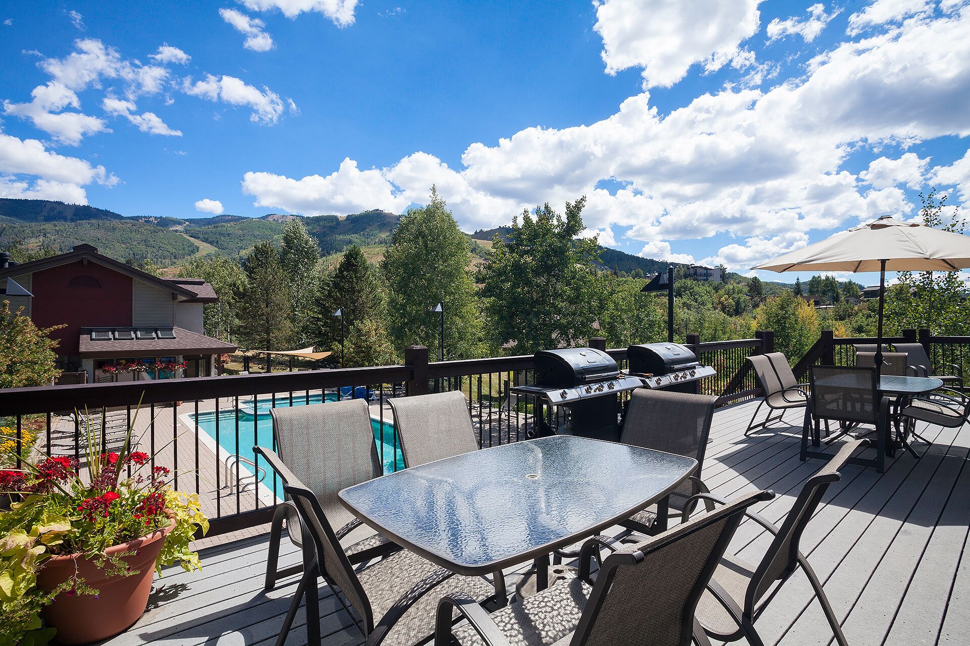Une terrasse avec une piscine, un espace salon extérieur et un barbecue.
