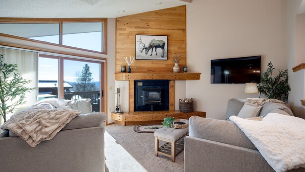 Un salón acogedor con chimenea, asientos cómodos y un amplio ventanal con vistas al exterior.