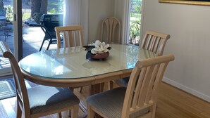 A dining area with a glass-top table surrounded by wooden chairs, a chandelier, and a painting on the wall. - Harbour Town Golf Links 11th Tee Ranch Walkable to Harbour Town (Hilton Head Island)