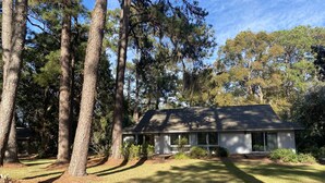 A single-story house with a gabled roof, surrounded by tall pine trees and a well-maintained lawn. - Harbour Town Golf Links 11th Tee Ranch Walkable to Harbour Town (Hilton Head Island)