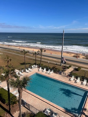 A pool with lounge chairs and a view of the ocean. - TOP FLOOR Spectacular Ocean and Pool View Condo  (Ormond Beach)