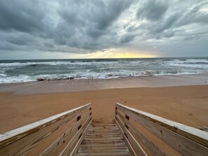 Una passerella di legno che conduce a una spiaggia sotto un cielo nuvoloso.