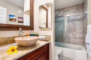A bathroom with a large stone sink, a mirror, a shower, and a toilet. - Banyan Tree 301: DIRECT OCEANFRONT 2/2 REMODELED WITH AIR CONDITIONING! (Kailua Kona)