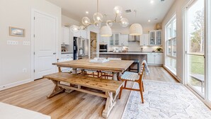 Un'ampia cucina con tavolo e panca in legno, elettrodomestici moderni e ampie finestre.