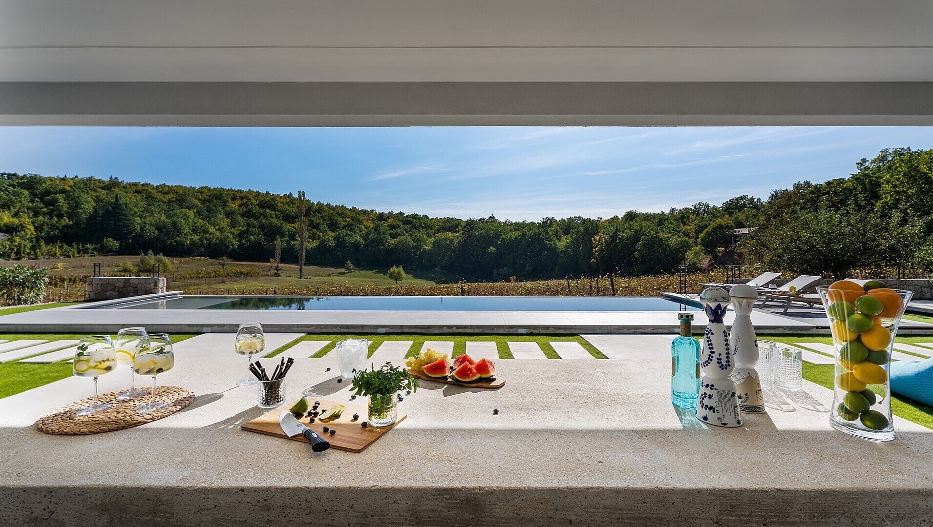A poolside setting with a view of a large pool and a forested area.
