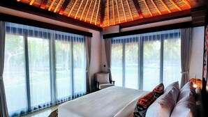 Un dormitorio amplio con una cama grande, una silla y vistas a una piscina.