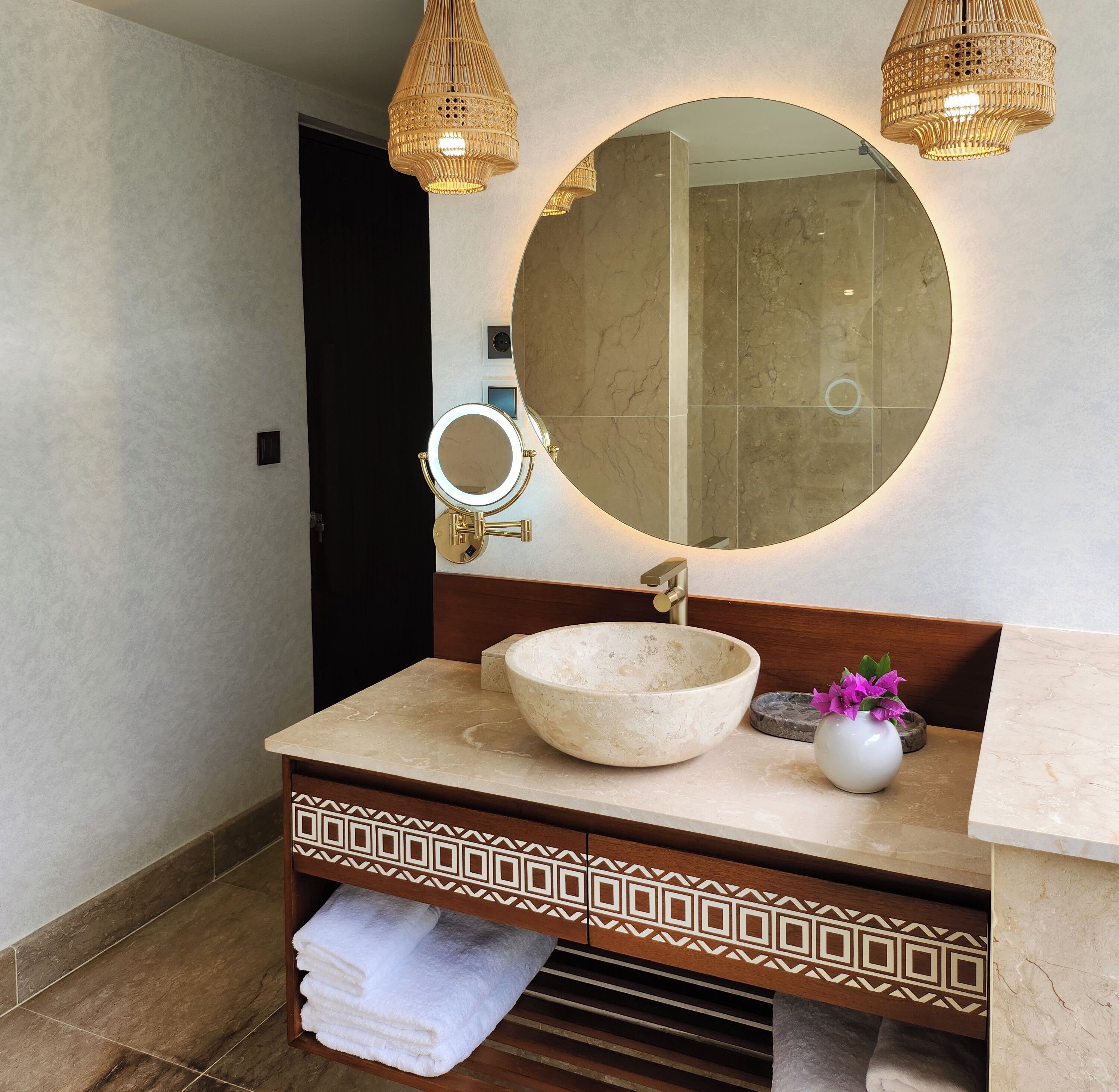 Un baño con un espejo redondo, un lavabo sobre encimera y dos luces fijadas a la pared.