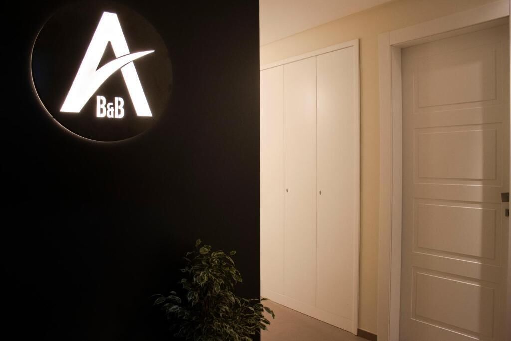 A hotel entrance with a prominent illuminated sign, a potted plant, and a closed door.