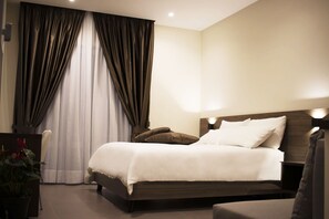 A neatly made bed with a headboard, a bedside table, and a lamp. - Augusto132 (Naples)