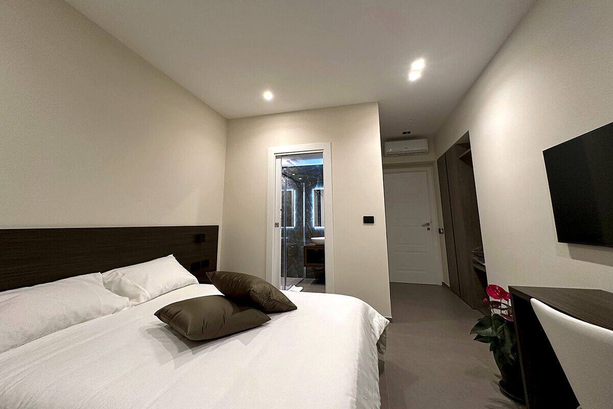 A hotel room with a large bed, a TV mounted on the wall, and a door leading to a bathroom.