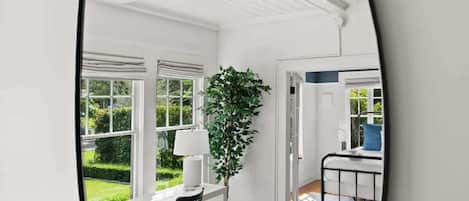 A modern interior with a wooden floor, white walls, and a large window.
