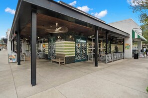 Enjoy a casual dining experience in our outdoor seating area with metal tables and chairs, sheltered by a flat roof.