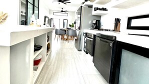 Een moderne keuken met witte kasten, zwarte apparatuur en een centraal eiland.