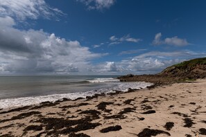 Una platja amb onades, roques i un cel serè.