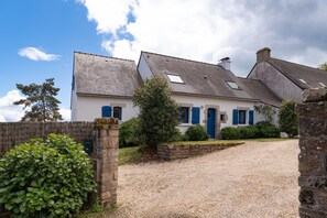A traditional house with a gravel driveway, stone walls, and a blue door.