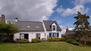 A two-story house with a sloped roof, a chimney, and a small balcony with blue shutters. - Holiday Home 'Maison Aux Volets Bleus - Sea View' with Private Terrace and Garden (Arzon)