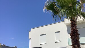Un bâtiment moderne doté d’un toit plat, de murs extérieurs blancs et d’un espace extérieur couvert agrémenté d’une pergola.