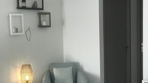 Un soggiorno moderno con un divano grigio, un tavolino rotondo con una candela, una lampada in vimini e una poltrona grigia con un cuscino decorato.