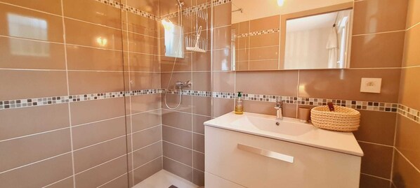 A modern bathroom with a glass shower enclosure, a white vanity with a mirror, and a tiled backsplash.