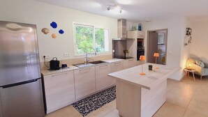Una cucina moderna con frigorifero integrato, un'isola centrale e un'area pranzo con tavolo e sedie.