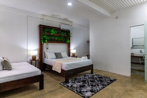 A modern bedroom with a wooden bed, a bedside table with a lamp, a black and white rug, and a green plant wall.