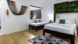 A bedroom with two beds, a window, a fire extinguisher, and a green wall decoration. - El Deseo Serendipity Hotel (Colorado)